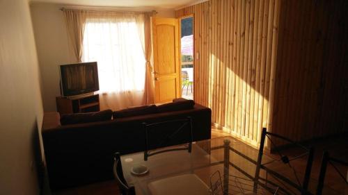 a living room with a couch and a television at Refugios Olmue Santa Teresa in El Maqui
