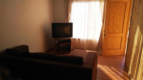 a living room with a couch and a television at Refugios Olmue Santa Teresa in El Maqui