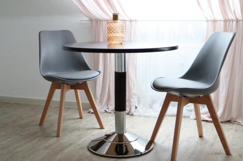 two chairs around a round table with a lamp on top at Buerpartment in Gelsenkirchen