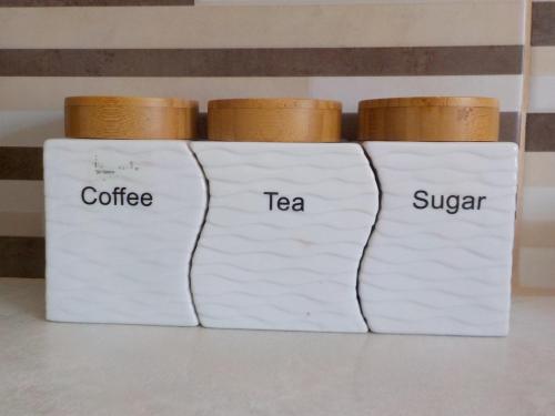 a group of three white containers with the words tea and sugar at *OI.KO HOUSE* City Apartments in Kato Achaia