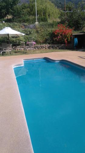 a large blue swimming pool with an umbrella at Refugios Olmue Santa Teresa in El Maqui