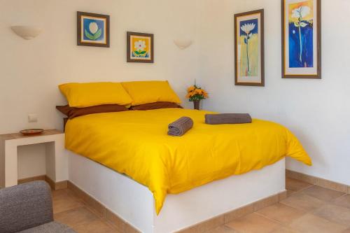 a bed with a yellow blanket on top of it at Casa dos Ninos in São Bartolomeu de Messines