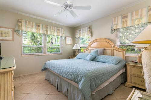 a bedroom with a bed with blue pillows and windows at Beach & Waterway RFV Resort BB in Hillsboro Beach