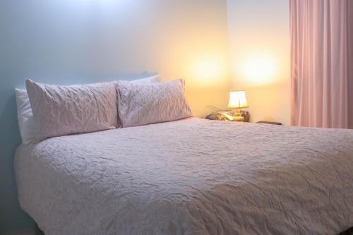 a bedroom with a white bed with a pillow and a lamp at Chin Cozy@ Rhyne Park in Montego Bay