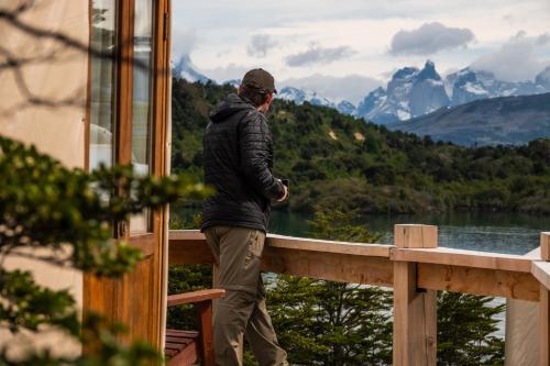 a man standing on a balcony looking out at a mountain at Patagonia Camp in Torres del Paine