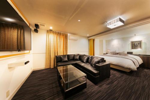 Habitación de hotel con cama y sofá en Hotel Eldia Modern Kobe(Adult Only) en Kobe