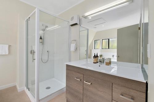 a white bathroom with a shower and a sink at Suburb Retreat in Queenstown