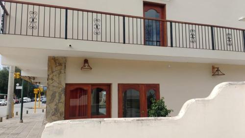 a white building with red doors and a balcony at Portal De Los Valles in Chicoana