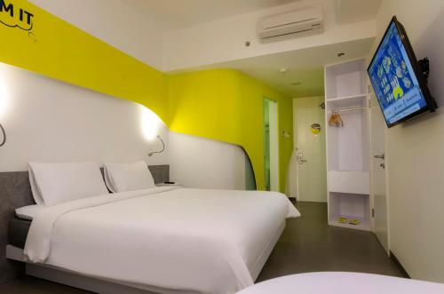 a bedroom with two beds and a tv on a wall at Yello Hotel Jemursari in Surabaya
