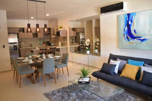 a living room with a blue couch and a dining room at Condo Lux Xareni in Playa del Carmen
