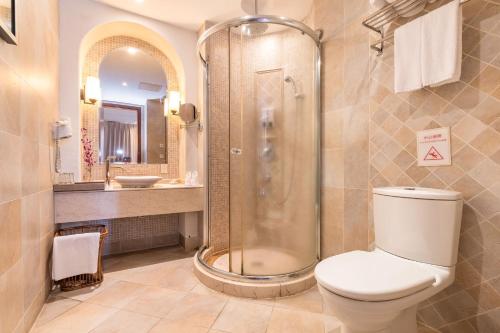 a bathroom with a shower and a toilet and a sink at Aegean Suites Sanya Yalong Bay Resort in Sanya