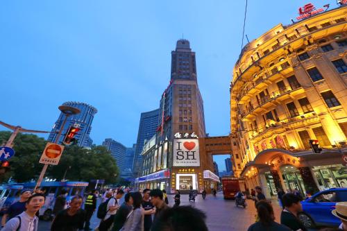 una folla di persone che camminano per una strada trafficata di Seventh Heaven Hotel a Shanghai