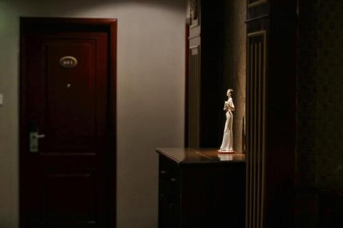 a statue of a woman sitting on a dresser in a room at Seventh Heaven Hotel in Shanghai