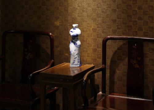 a vase sitting on a table next to two chairs at Seventh Heaven Hotel in Shanghai