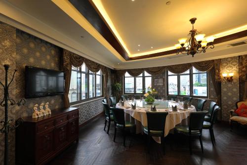 a dining room with a table and chairs and a television at Seventh Heaven Hotel in Shanghai
