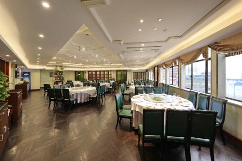 a dining room with tables and chairs and windows at Seventh Heaven Hotel in Shanghai