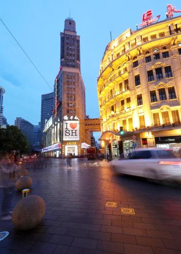 a city street with buildings and a car driving past at Seventh Heaven Hotel in Shanghai
