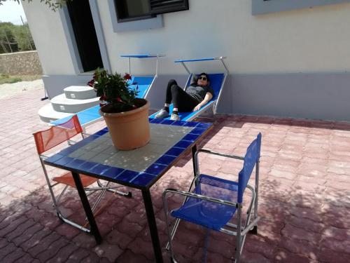 una persona seduta su un letto con tavolo e sedie di Casuzza cala pisana a Lampedusa