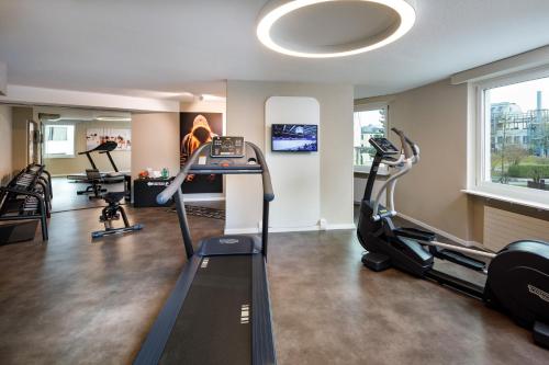 a gym with treadmills and exercise bikes in a room at Hotel Welcome Inn in Kloten