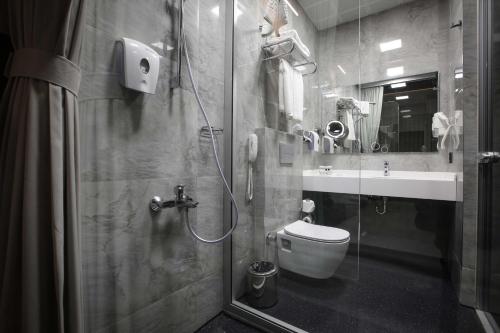 a bathroom with a shower and a toilet and a sink at Best Western Premier Karsiyaka Convention & Spa Hotel in Izmir