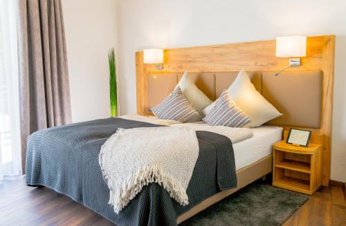 Schlafzimmer mit einem großen Bett mit einem Kopfteil aus Holz in der Unterkunft Landhotel Lebensart in Xanten