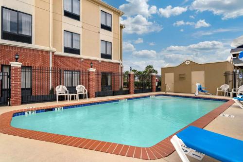 a swimming pool with chairs and a building at Comfort Inn & Suites Port Arthur-Port Neches in Port Arthur