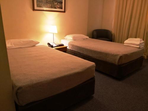 a hotel room with two beds and a chair at Criterion Hotel Perth in Perth