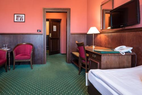 a hotel room with a bed and a desk with a telephone at Hotel U Hejtmana Šarovce in Uherské Hradiště