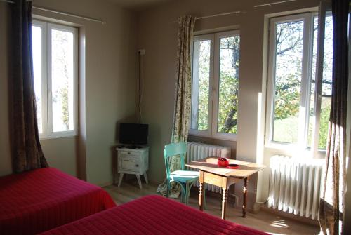 sypialnia z łóżkiem, stołem i oknami w obiekcie Hôtel Restaurant les Platanes w mieście Montfaucon