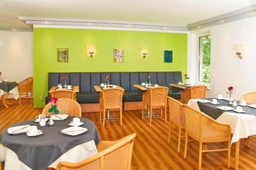 Hotel BonaMari في زالتسغيتر: مطعم به طاولات وكراسي وجدران خضراء