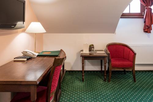 a room with a desk and a red chair and a telephone at Hotel U Hejtmana Šarovce in Uherské Hradiště