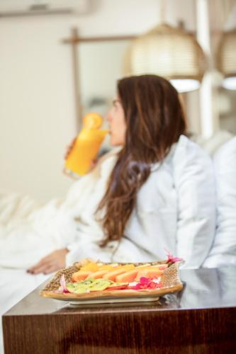 a woman sitting in a bed with a plate of food at Solare SAI Ecohotel in San Andrés