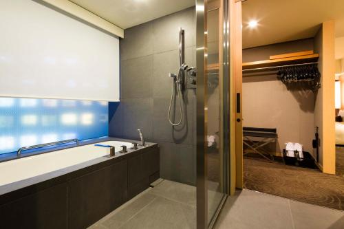 a bathroom with a shower and a sink and a tub at The Capitol Hotel Tokyu in Tokyo