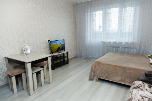 ノヴォシビルスクにあるApartament Antonina near by Marriott hotelのベッドルーム(ベッド1台、テーブル、テレビ付)