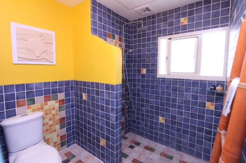 baño de azulejos azules con aseo y ventana en Kending Hai Zhi Lian B&B, en Eluan