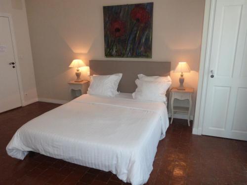 a bedroom with a large white bed with two lamps at Hotel La Closeraie in Sully-sur-Loire