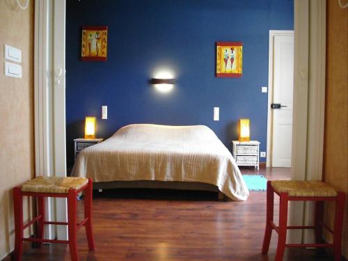 - une chambre avec un lit aux murs bleus et 2 chaises dans l'établissement Appartement 