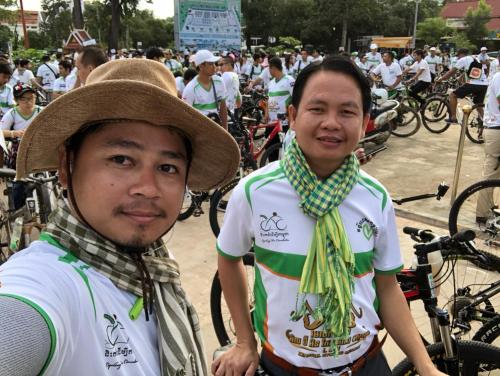 two men wearing hats and ties standing in a crowd of bikes at Blossoming Romduol Boutique in Siem Reap