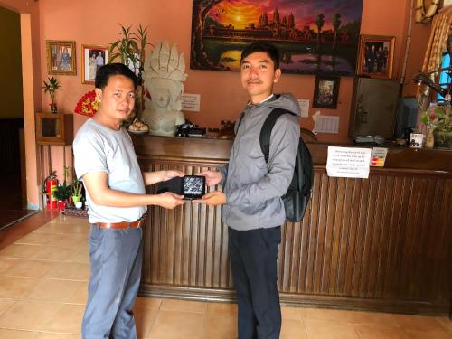 two men standing in front of a bar holding a cell phone at Blossoming Romduol Boutique in Siem Reap