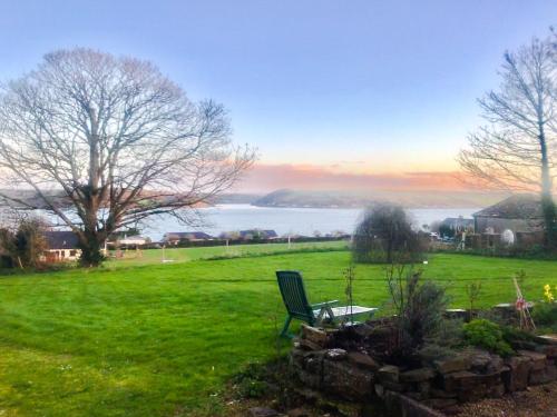 a green bench in a field with a view of the water at Tranquil Water in Midleton