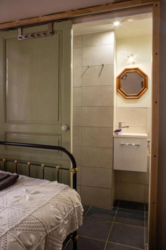 une chambre avec un lit, un miroir et un lavabo dans l'établissement Chez les Amis, à Saint-Nazaire-de-Ladarez