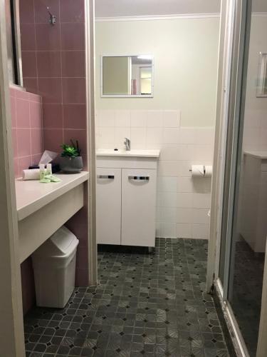 a bathroom with a sink and a toilet and a mirror at OCEAN BREEZE MOTEL in Port Macquarie