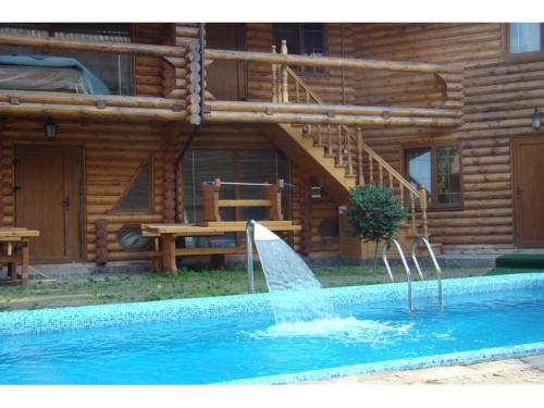 una fuente en una piscina frente a una cabaña de madera en Dvorik en Chernivtsi