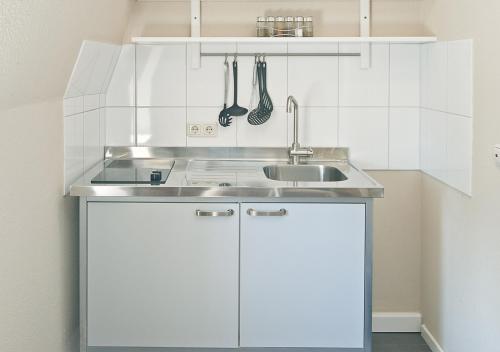 una cocina con armarios blancos y fregadero en Ferienwohnung Crames, en Trier