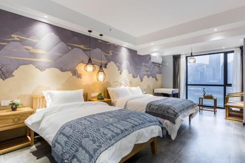 two beds in a room with a mural on the wall at Chongqing Ouranjian Lake View Guesthouse in Chongqing