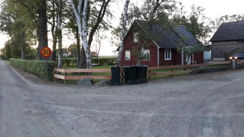 a red house with two trash cans on the side of a road at Hus på Lantgård Viken in Mjöhult