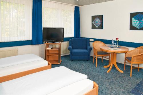 um quarto com duas camas e uma televisão e uma mesa em Hotel BonaMari em Salzgitter