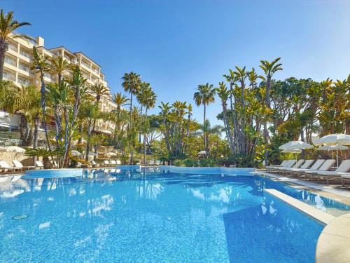 a large swimming pool with chairs and palm trees at Ria Park Hotel & Spa in Vale do Lobo