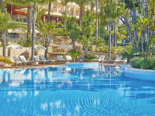 a large swimming pool with chairs and palm trees at Ria Park Hotel & Spa in Vale do Lobo