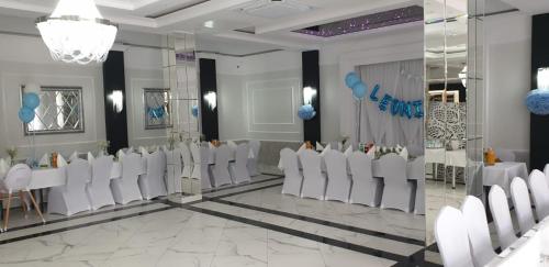 a banquet hall with white chairs and tables and blue balloons at Zacisze in Sokółka